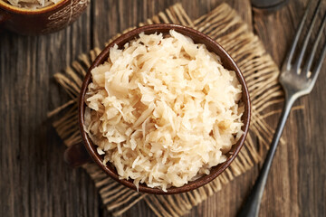 Homemade fermented cabbage or sauerkraut in a clay pot on a table, top view