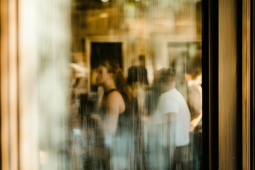 Blurry image of a group of people in a bar seen through the window glass.