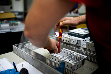 Electrician, engineer assembles an electrical cabinet in a factory.