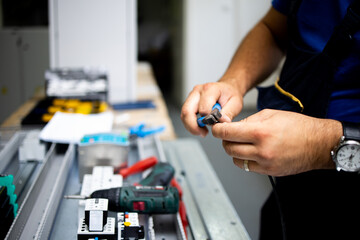 Electrician, engineer assembles an electrical cabinet in a factory.