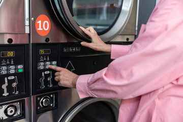 Close up picture of female hand programming washing machine