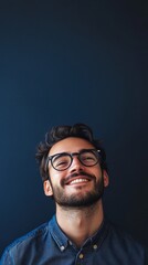 Fototapeta premium nerdy man with glasses smiling at camera on dark blue background with copy space vertically 9:16