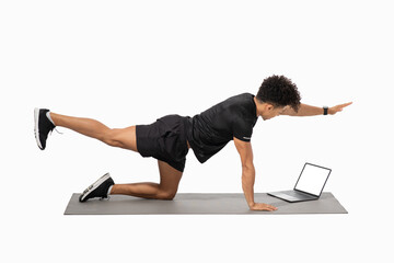 A young Brazilian man engages in an athletic workout routine at home, utilizing a laptop for guidance. He showcases a strong focus on maintaining healthy lifestyle habits.