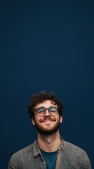 nerdy man with glasses smiling at camera on dark blue background with copy space vertically 9:16