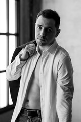 Black and white portrait of young handsome sexy man in a shirt in a loft interior