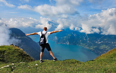 A tourist stands on a hilltop with arms wide open.
