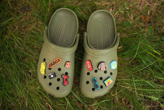 Warsaw, Poland - July 29, 2024: pair of green Crocs sneakers with the Jibbitz logo outdoors.