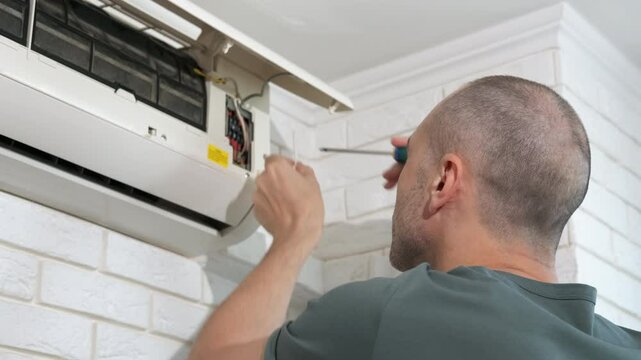 Engineer fixing equipment on wall cooling system. A view of service man fixing the parts of cooling system at home conditioner indoor.