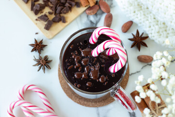 Cup of homemade hot chocolate drink with sweet candy canes on white kitchen table. Top view.