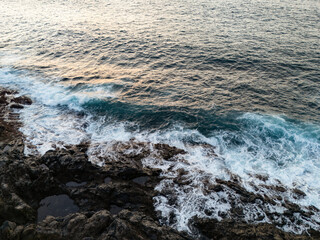 Atlantic ocean sunset in Tenerife, waves gently crashing against the rocky shore.  A scene that evokes a sense of tranquility and connection with nature