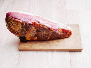 Famous Spanish dry ham on a wooden holder board on wooden table surface. Fine, worldwide popular product. Premium special pork meat.
