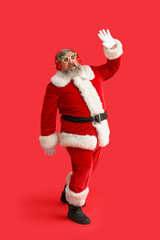 Funny Santa Claus in headphones listening to music and dancing on red background