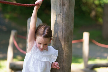 Little cute girl without front tooth rope playground summer park. Concept of active healthy...