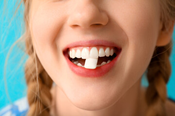 Obraz premium Teenage girl chewing gum on blue background, closeup