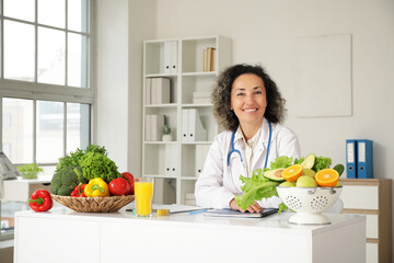 Mature female nutritionist sitting at table in office