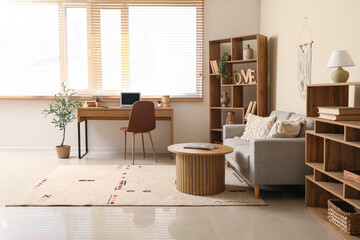 Interior of stylish modern living room with grey sofa, shelving units and laptop on table