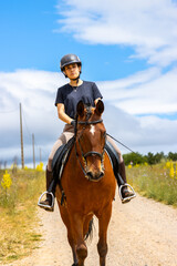 Female equestrian riding a horse on a countryside road