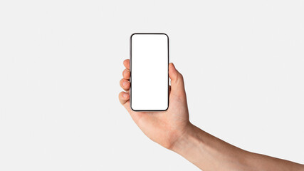 Male hand presenting smartphone with blank screen over light background, mockup for design. Panorama