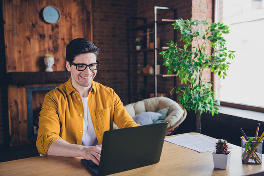 Young man in stylish shirt enjoying a relaxed day indoors, working happily on laptop in bright and cozy home interior