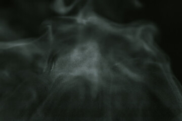 A dark and moody abstract image of swirling green smoke patterns, creating a mysterious and...