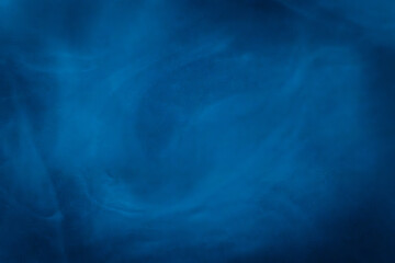 A close-up of soft, swirling blue smoke patterns creating an ethereal and dreamy abstract effect against a dark background