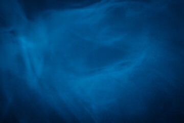 A close-up of soft, swirling blue smoke patterns creating an ethereal and dreamy abstract effect against a dark background