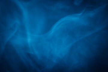 A close-up of soft, swirling blue smoke patterns creating an ethereal and dreamy abstract effect against a dark background