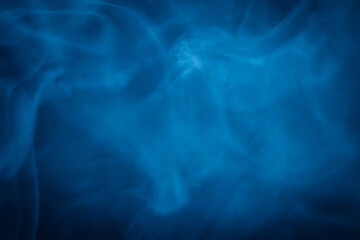 A close-up of soft, swirling blue smoke patterns creating an ethereal and dreamy abstract effect against a dark background