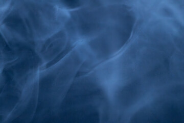 A close-up of soft, swirling blue smoke patterns creating an ethereal and dreamy abstract effect against a dark background
