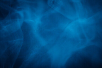 A close-up of soft, swirling blue smoke patterns creating an ethereal and dreamy abstract effect against a dark background