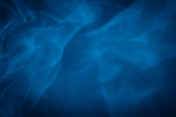A close-up of soft, swirling blue smoke patterns creating an ethereal and dreamy abstract effect against a dark background