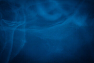 A close-up of soft, swirling blue smoke patterns creating an ethereal and dreamy abstract effect against a dark background