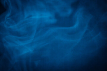 A close-up of soft, swirling blue smoke patterns creating an ethereal and dreamy abstract effect against a dark background