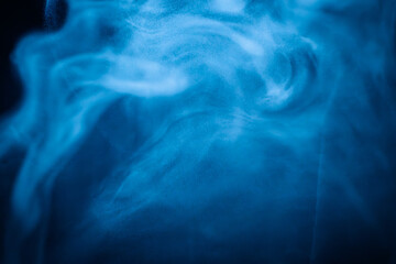 A close-up of soft, swirling blue smoke patterns creating an ethereal and dreamy abstract effect against a dark background