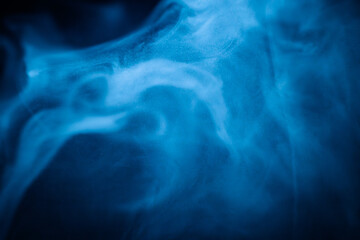A close-up of soft, swirling blue smoke patterns creating an ethereal and dreamy abstract effect against a dark background