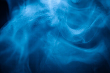 A close-up of soft, swirling blue smoke patterns creating an ethereal and dreamy abstract effect against a dark background