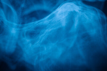 A close-up of soft, swirling blue smoke patterns creating an ethereal and dreamy abstract effect against a dark background