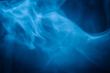 A close-up of soft, swirling blue smoke patterns creating an ethereal and dreamy abstract effect against a dark background