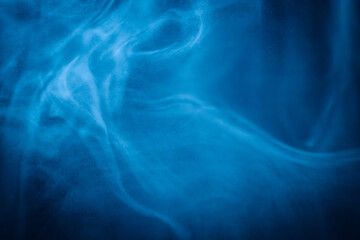A close-up of soft, swirling blue smoke patterns creating an ethereal and dreamy abstract effect against a dark background