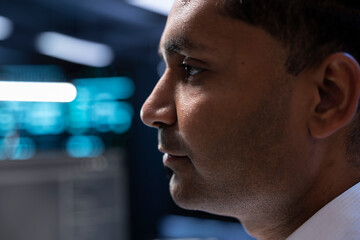Technician in high tech facility walking through server rigs used for computationally intensive...