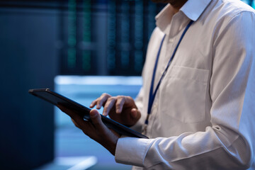 Engineer working in high tech server farm, using laptop and tablet to analyze data, ensuring seamless data flow. Man examining hardware in data center, ensuring system integrity and security, close up