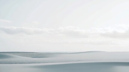 Obraz premium Vast and tranquil desert landscape with rolling sand dunes under a soft, cloudy sky, showcasing minimalist beauty and natural textures in a serene and expansive environment.