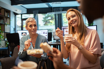Office coworkers enjoying lunch break and chatting at workplace