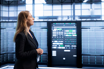 Engineer walking between server rows in data center, doing yearly infrastructure inspection. System...