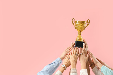 Many hands with gold cup on pink background