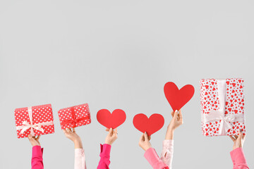 Female hands with hearts and gift boxes on light background. Valentine's Day celebration