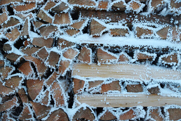 Ein Stapel Brennholz mit Schnee und Raureif im Winter
