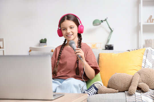 Cute girl with microphone recording podcast at home