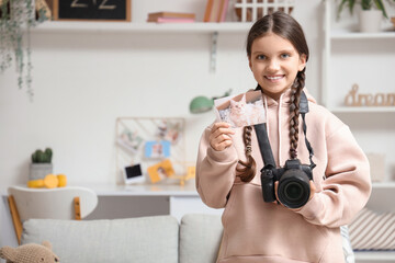 Cute girl with photo camera and picture at home