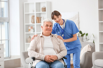 Obraz premium Female doctor hugging mature man in wheelchair at home